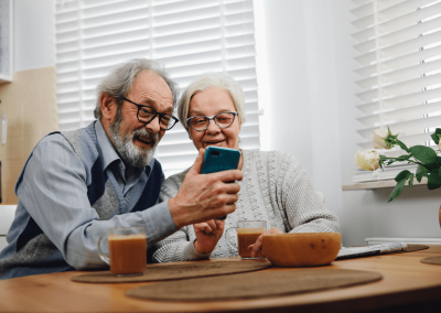 Couple âgé heureux consulte leurs finances sur appareil mobile. Augmentation de la pension de vieillesse