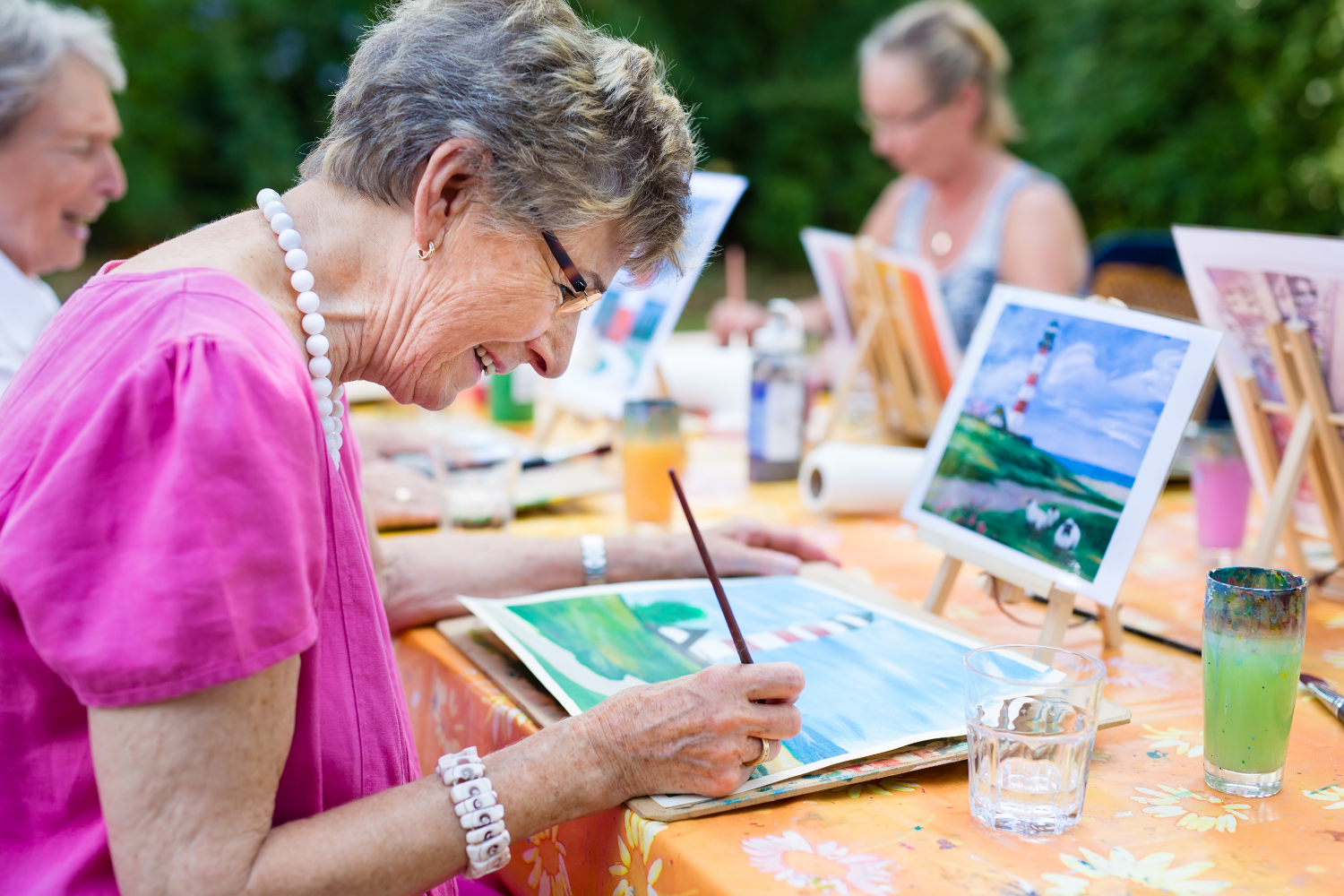 Femme aînée qui peinture avec ses amies dehors à leur résidence pour aînés.